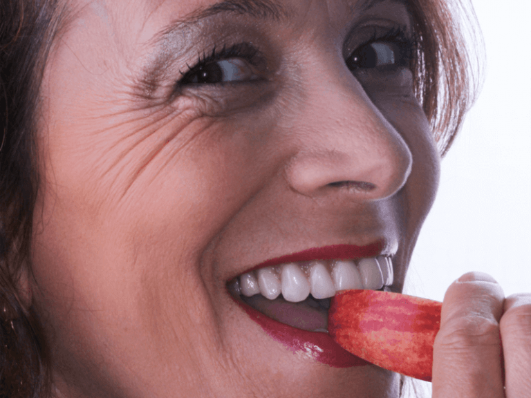 imagem de paciente a trincar uma maça depois de colocar implante dentário